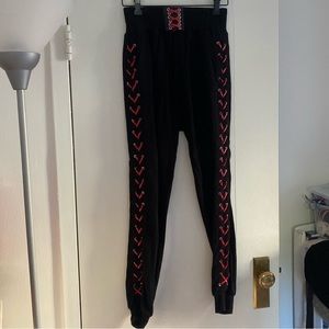 The Kooples black sweatpants with red leather corset detail at the side